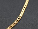 a close up of a gold chain on a black surface