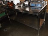 une grande table en acier inoxydable au milieu d'une cuisine