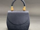 a grey purse with a wooden handle on a gray background