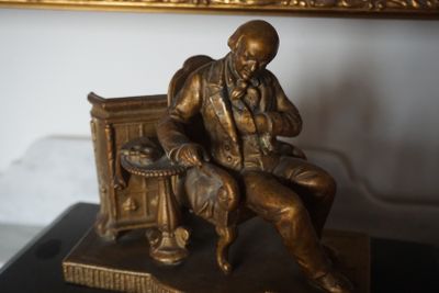 une statue en bronze représentant un homme assis sur un banc