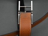 brown leather belt with a silver buckle on a gray surface