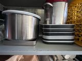 Plusieurs casseroles et poêles sont empilées sur une étagère dans une cuisine