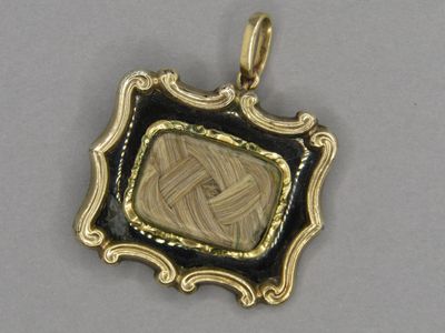 a close up of a gold and black pendant with a picture in it