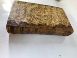 an old book sitting on top of a white table next to a cup