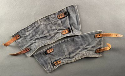two pieces of denim with leather straps on a gray surface