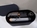 a black box with a silver and gold hair dryer and a brush in it