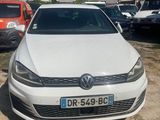 a white volkswagen golf parked in a parking lot next to other cars