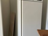 white refrigerator freezer sitting in a kitchen next to a wooden table
