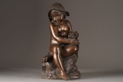 bronze statue of a boy sitting on a rock with a cat