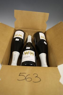 trois bouteilles de vin dans un carton sur une table