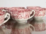 several red and white cups and saucers are lined up on a table