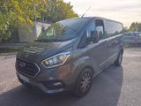 La camionnette grise est garée sur un parking, avec des arbres en arrière-plan.