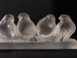 four glass birds sitting on top of a white tray