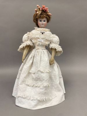 une poupée ancienne en porcelaine représentant une femme en robe blanche