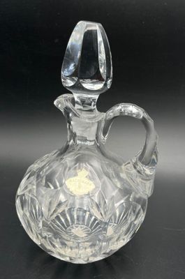 an image of a clear glass bottle with a handle on a black surface