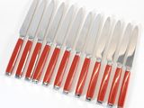 six knives with red handles are lined up on a white surface
