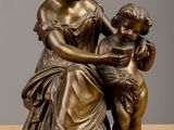 bronze statue of a woman reading to a child on a table