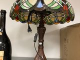 a lamp that is sitting on a shelf next to a bottle of wine