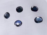 six blue sapphires are arranged on a white surface