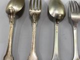 three silver spoons and a fork are lined up on a table