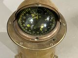 a small brass compass sitting on a white surface