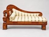 une chaise longue ancienne en bois avec des coussins rembourrés à rayures