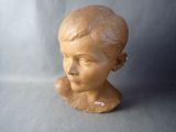 a clay head of a young boy on a gray background
