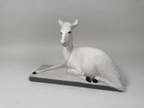 statue d'un cerf blanc assis sur une dalle de pierre