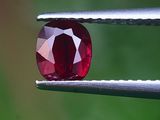 un gros plan d'un diamant rouge tenu par une pince