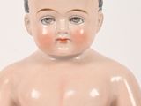 a baby doll that is sitting on a white surface