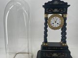 a clock that is under a glass dome on the table