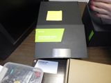 une boîte noire sur laquelle est collé un autocollant jaune, posée sur un bureau