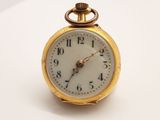 une montre de poche en or posée sur une surface blanche