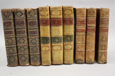 six old books are lined up in a row on a white surface