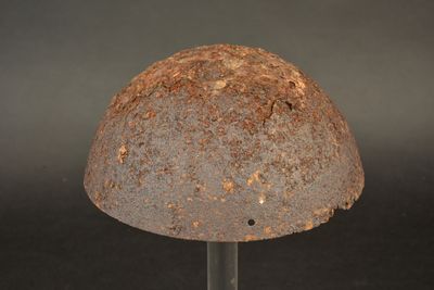 an old rusty helmet sitting on a metal stand
