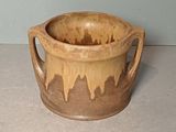 a brown cup sitting on a table with a handle