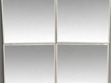 four square mirrors on a wall in a room with grey walls
