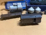 Plusieurs petits trains sont alignés sur une table, à côté d'une boîte