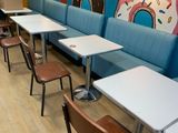 many tables and chairs in a restaurant with a man standing in the background