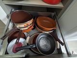 many pots and pans in the drawer of a kitchen