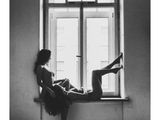 photographie en noir et blanc d'une femme assise sur le rebord d'une fenêtre