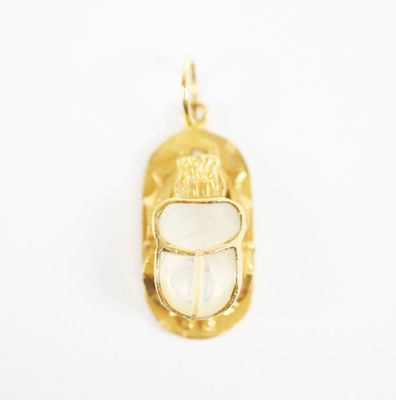 a close up of a gold plated pendant with a white shell