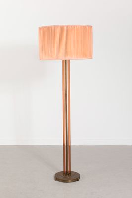 Le lampadaire est en bois et est doté d'un abat-jour rose