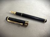 two black and gold fountain pens sitting on top of a table
