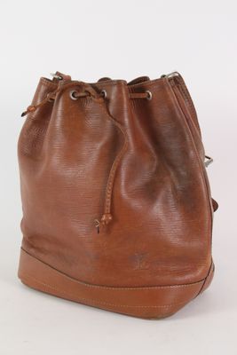 une photo d'un sac seau en cuir marron posé sur une surface blanche