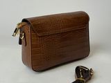 a brown crocodile skin purse with a leash on a white background