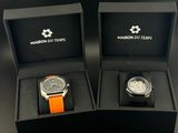 deux montres dans des boîtes noires, munies de bracelets orange