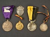 three medals and a purple ribbon on a black surface