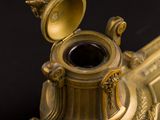 a gold vase with a black lid on a black table