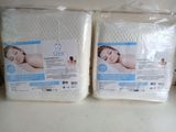 two packs of white mattress covers sitting on top of a counter